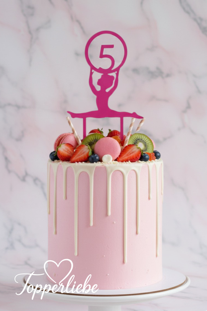 Rosa Kuchen mit weißem Drip und pinkem Akrobatin Torten Topper mit Hula-Hoop und Zahl im Kreis – dekoriert mit Beeren und Makronen, ideal für sportliche Geburtstage