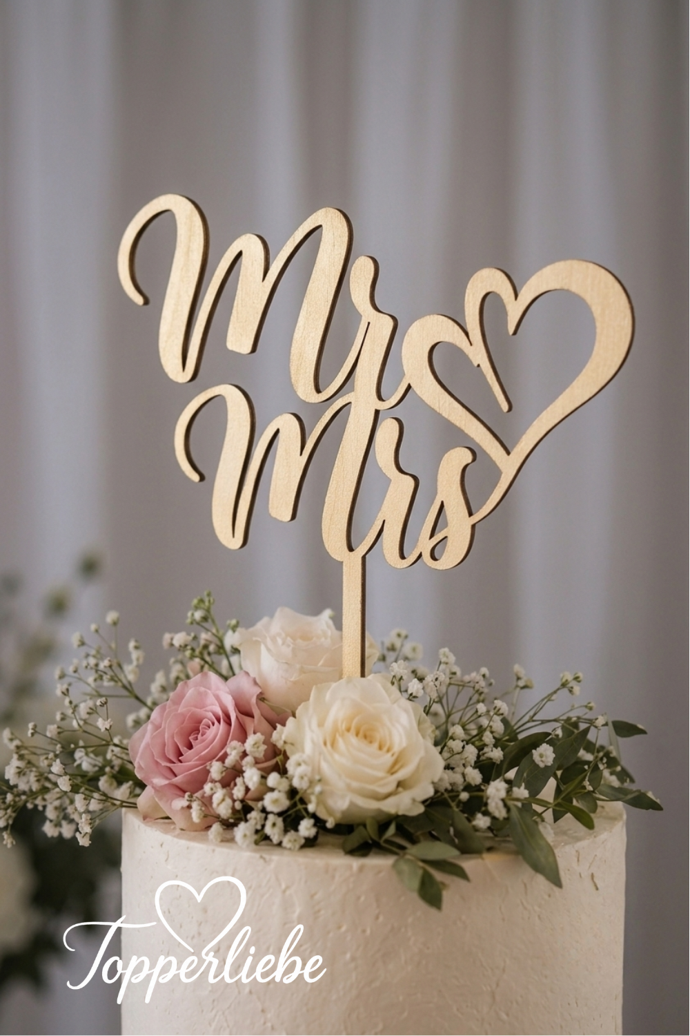Moderner Cake Topper „Mr &amp; Mrs“ mit Herz als elegante Tortendekoration auf einer stilvollen Hochzeitstorte mit floralen Akzenten.