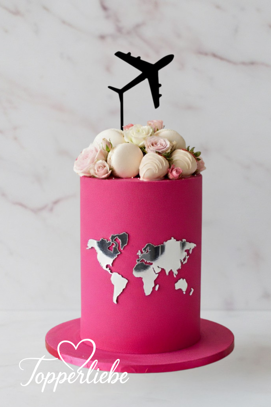 Rosa Kuchen mit silberner Weltkarte und schwarzem Flugzeug Torten Topper – moderne Reisedeko mit Blumen und Meringues, ideal für Weltenbummler