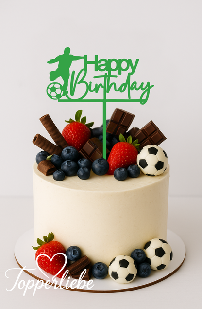 Moderner Tortentopper in Grün mit Fußballspieler und Schriftzug „Happy Birthday“ auf einer hellen Geburtstagstorte, dekoriert mit Beeren, Schokolade und kleinen Fußballdeko-Kugeln.