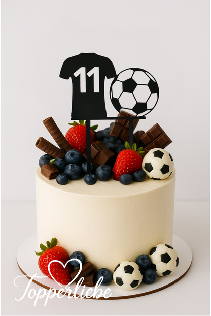 Personalisierter Fußball-Torten-Topper in Form eines Trikots mit Zahl und Ball auf einem hellen Geburtstagstorte mit Früchten und Schokolade.