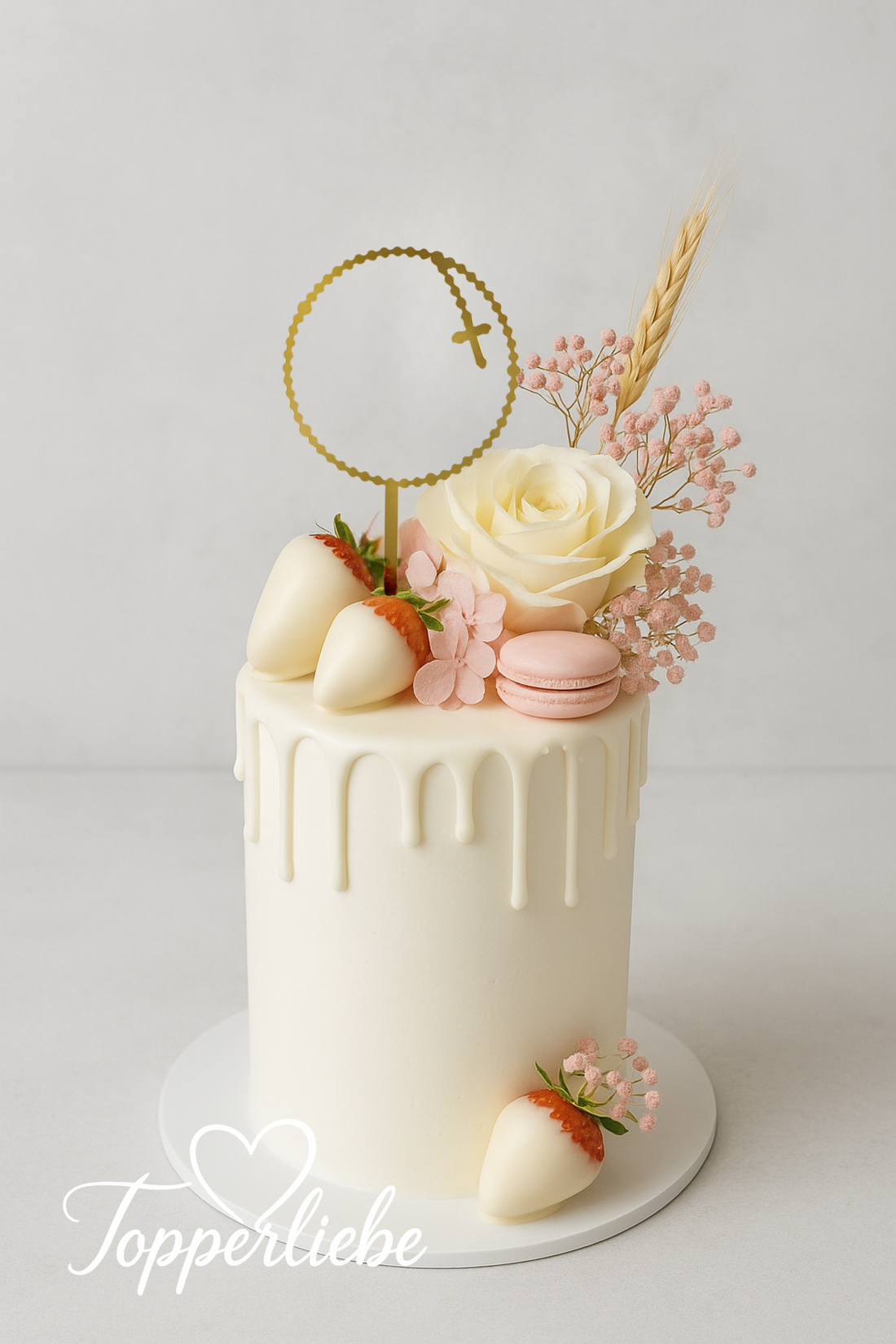 Elegante weiße Kommunionstorte mit goldenem Kreuz-Topper, weißen Rosen, rosa Blumen, Macarons und Weizengarbe – stilvolle Tortendeko von Topperliebe
